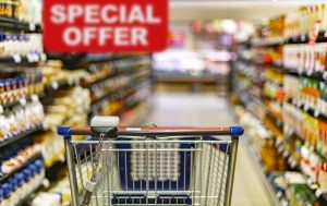 A shopping cart by a store shelf in a supermarket